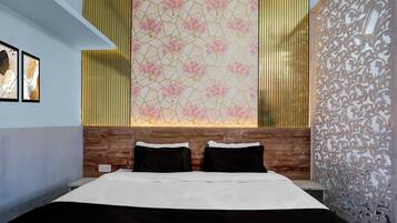 Habitación de hotel con una cama, dos almohadas, un cabecero de madera, una pared decorativa con un motivo geométrico y una ventana con persianas verticales.