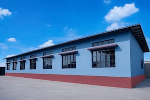 Un edificio con techo plano, múltiples ventanales y fachada azul y roja.