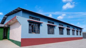 Un edificio de dos pisos con techo plano y fachada roja y azul.