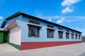 A two-story building with a flat roof and a red and blue facade. - Collection O Jalukbari Bus Stand (Guwahati)