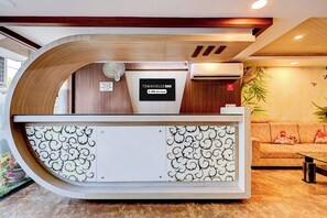 A reception desk with a check-in/out sign, an air conditioning unit, and a 'No Smoking' sign.