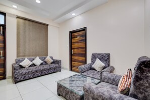 A modern living room with a sofa, armchair, and glass coffee table.