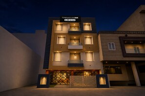 A multi-story building with balconies and a sign indicating it is serviced by OYO.