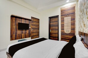 A modern bedroom with a large bed, a flat-screen TV mounted on a wooden panel wall, and a wardrobe with a mirror.