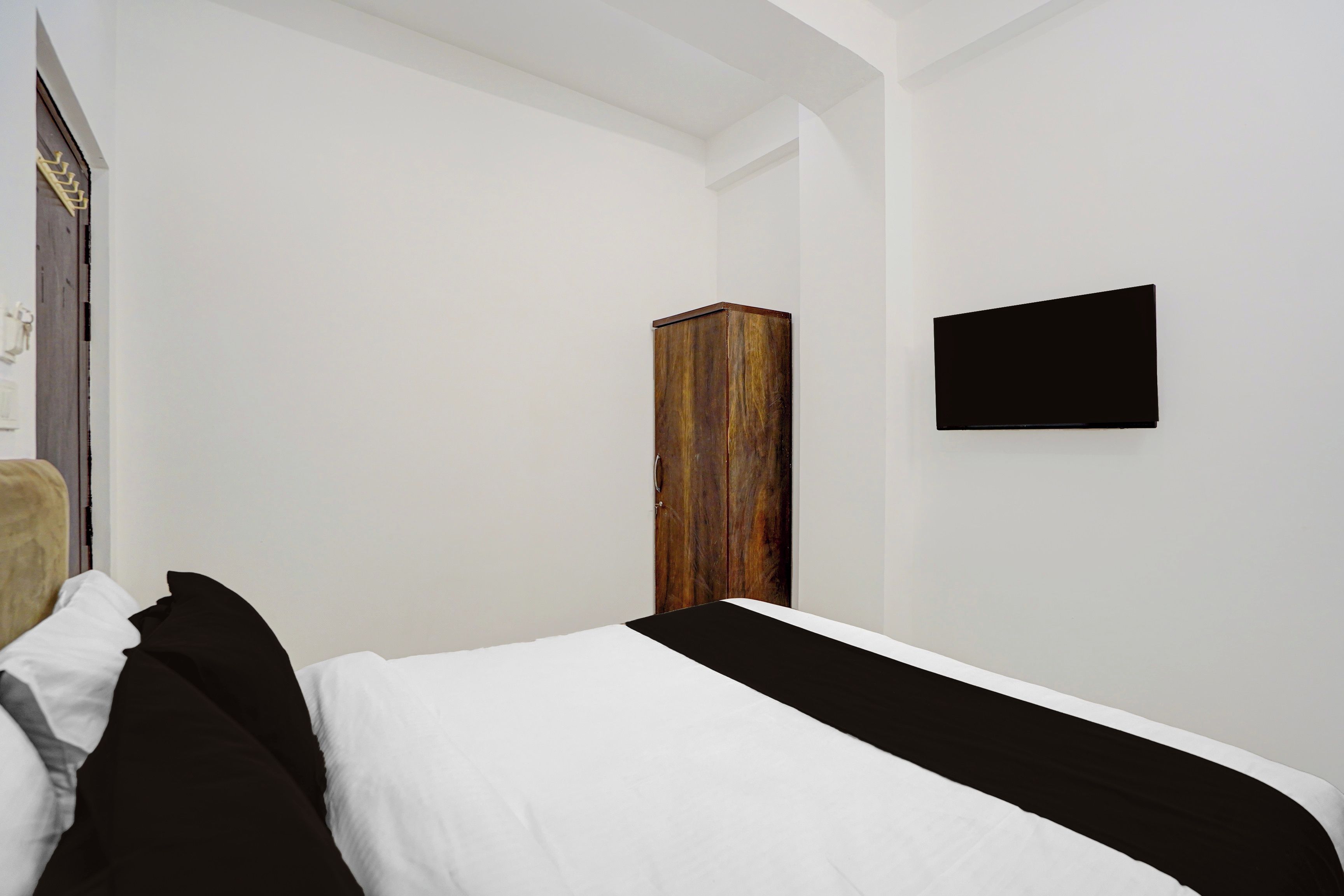 Een slaapkamer met een bed, een kledingkast en een flatscreen televisie aan de muur.