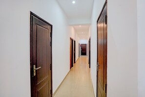 A corridor with wooden doors and white walls, leading to a room at the end. - Hotel O Gomti Nagar Station (Lucknow)