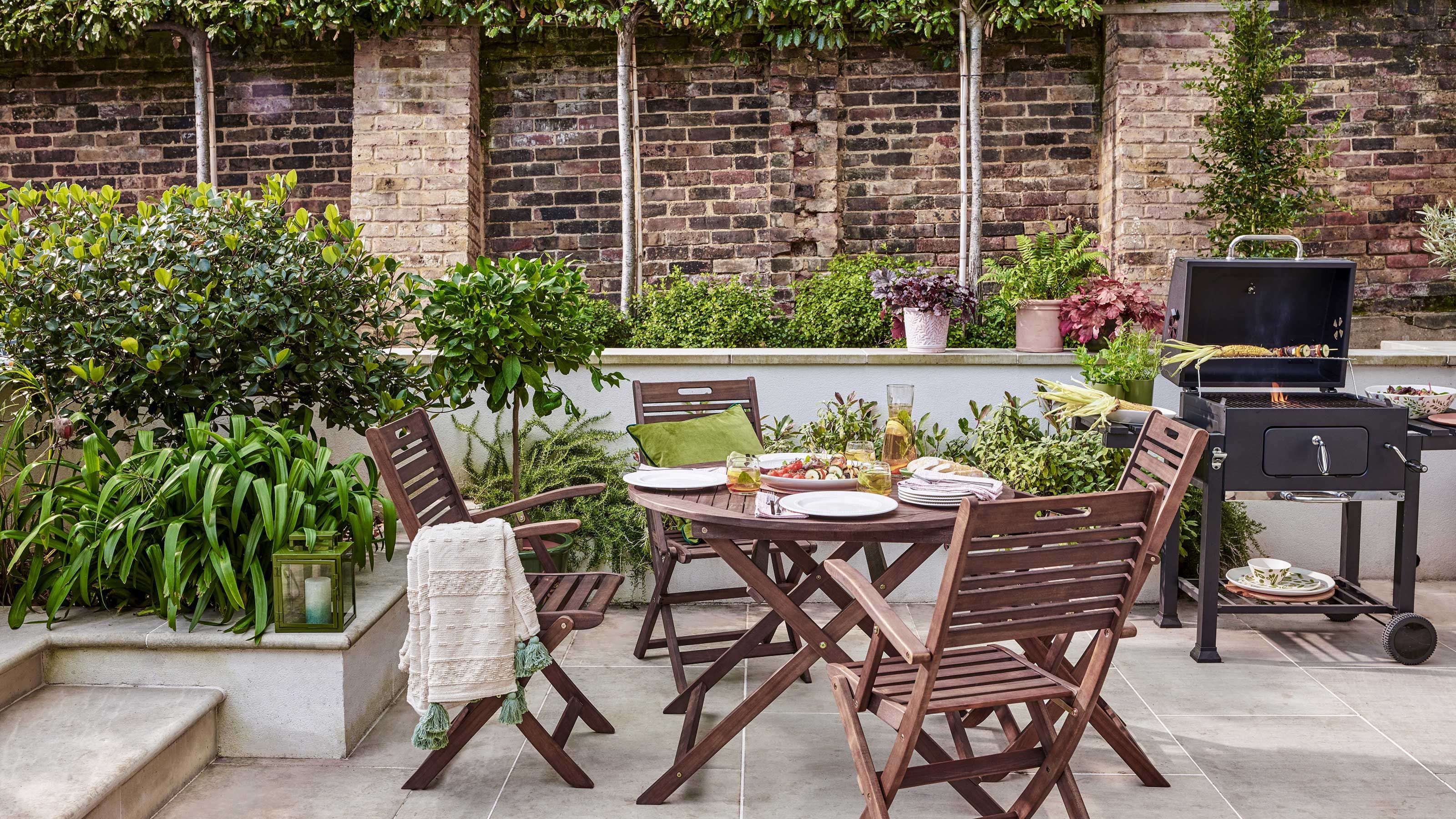 Une terrasse extérieure avec un mur en briques, un barbecue et diverses plantes.