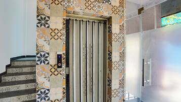 Un ascensor moderno con pared de azulejos estampados y puerta de metal.
