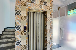 A modern elevator with a patterned tile wall and a metal door. - Hotel O Gomti Nagar Station (Lucknow)