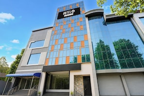 A modern hotel building with a prominent sign, large windows, and a staircase leading to the entrance. - Hotel O Gomti Nagar Station (Lucknow)