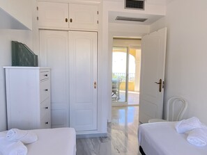 A hotel room with a wardrobe, a bed with a rolled towel, and a view of the balcony. - Holiday Home in Nerja With Sea Views (Nerja)