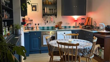 A kitchen with a dining table, chairs, and various kitchen appliances.