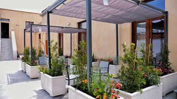 An outdoor seating area with covered tables and planters with various plants.
