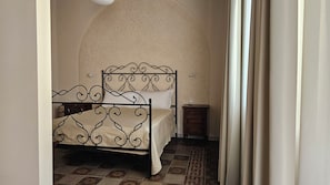 A bedroom with a bed, a nightstand, and a wall-mounted light fixture.