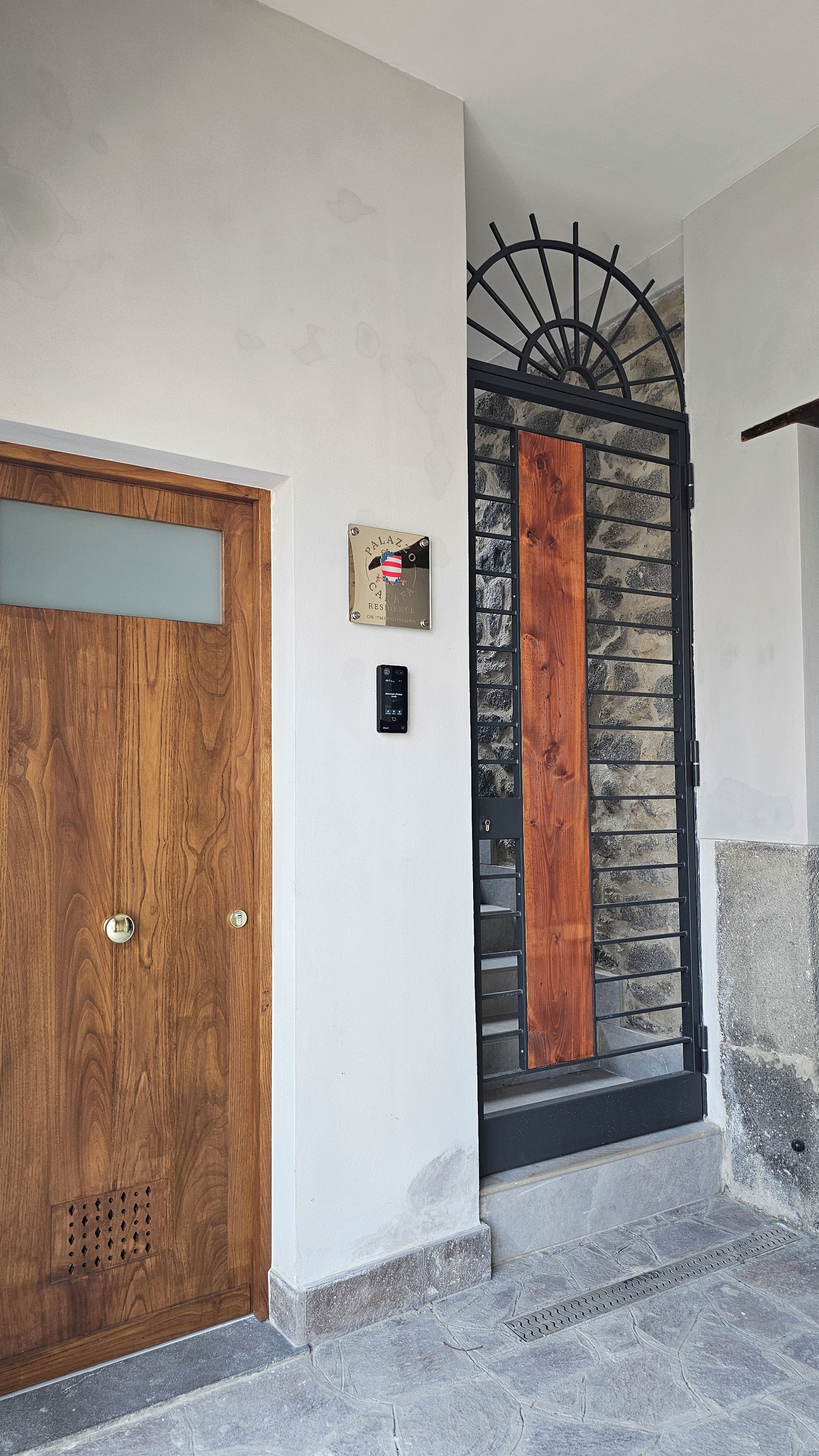 Una puerta de madera con un pomo de metal, una placa con el texto 'PALAZZO RESORT' y un portón de metal negro con un panel de madera.