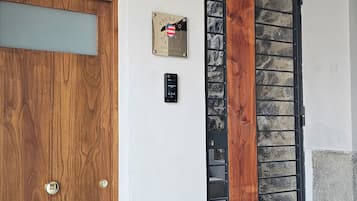 Una puerta de madera con un pomo de metal, una placa con el texto 'PALAZZO RESORT' y un portón de metal negro con un panel de madera.