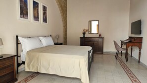 Un dormitorio con cama, escritorio, silla, cómoda y televisor.