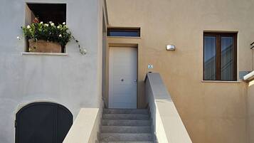 A building with a staircase leading to a door, a window, and a planter with flowers.