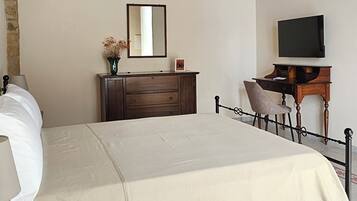 A bedroom with a bed, a dresser, a TV, and a ceiling fan.