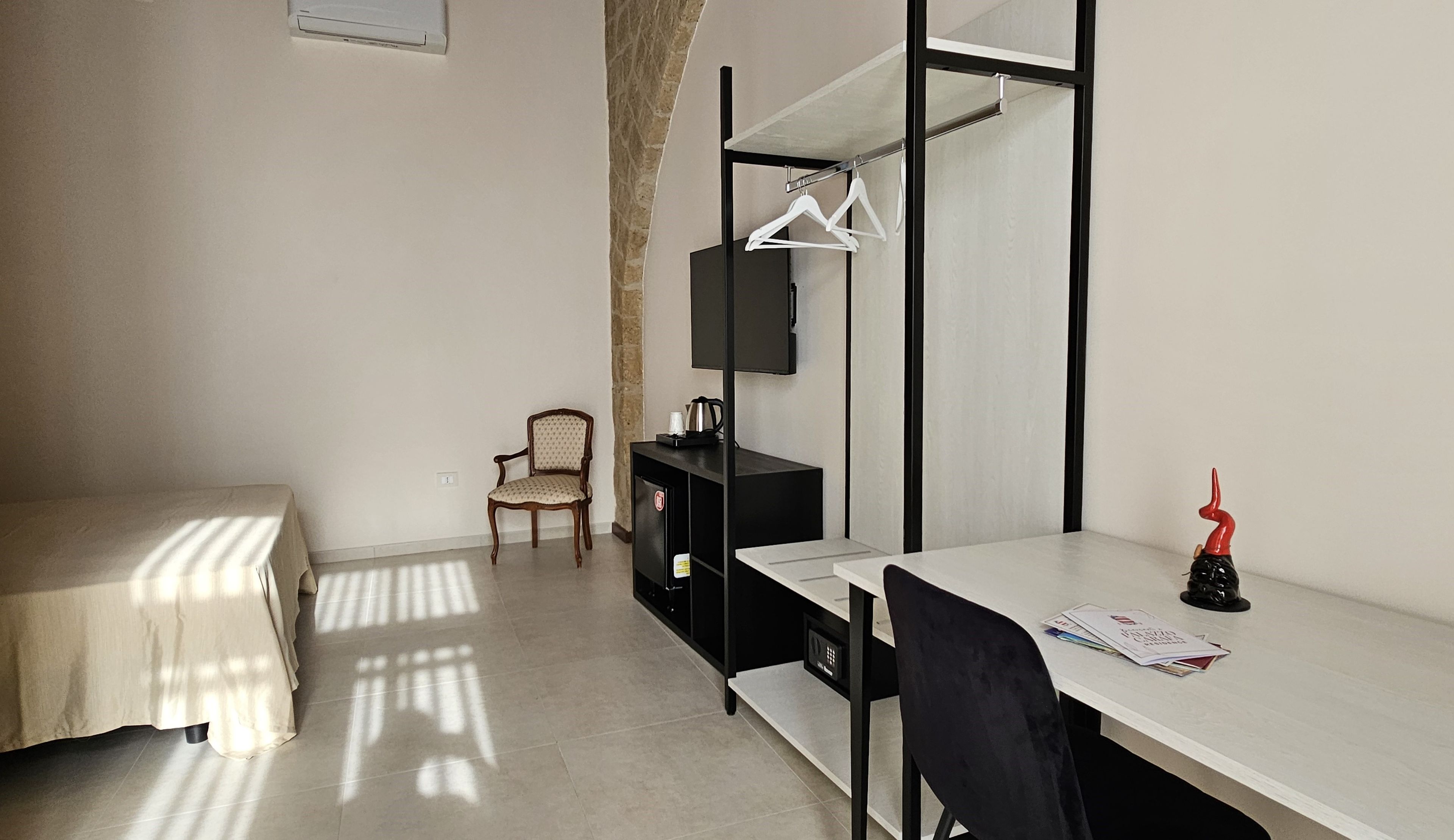 Una habitación pequeña y bien iluminada con una cama, un escritorio, una silla y un televisor.