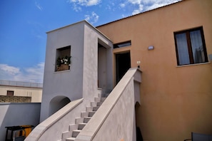A modern building with a staircase leading to a door, a window, and a small balcony with flowers.
