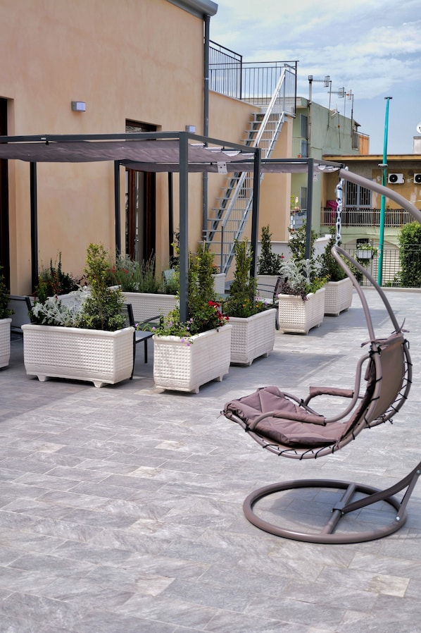 An outdoor seating area with cushioned chairs and planters.