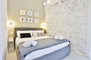 Een hotelkamer met een bed, een nachtkastje, een wand met een structuur en ingelijste foto's.