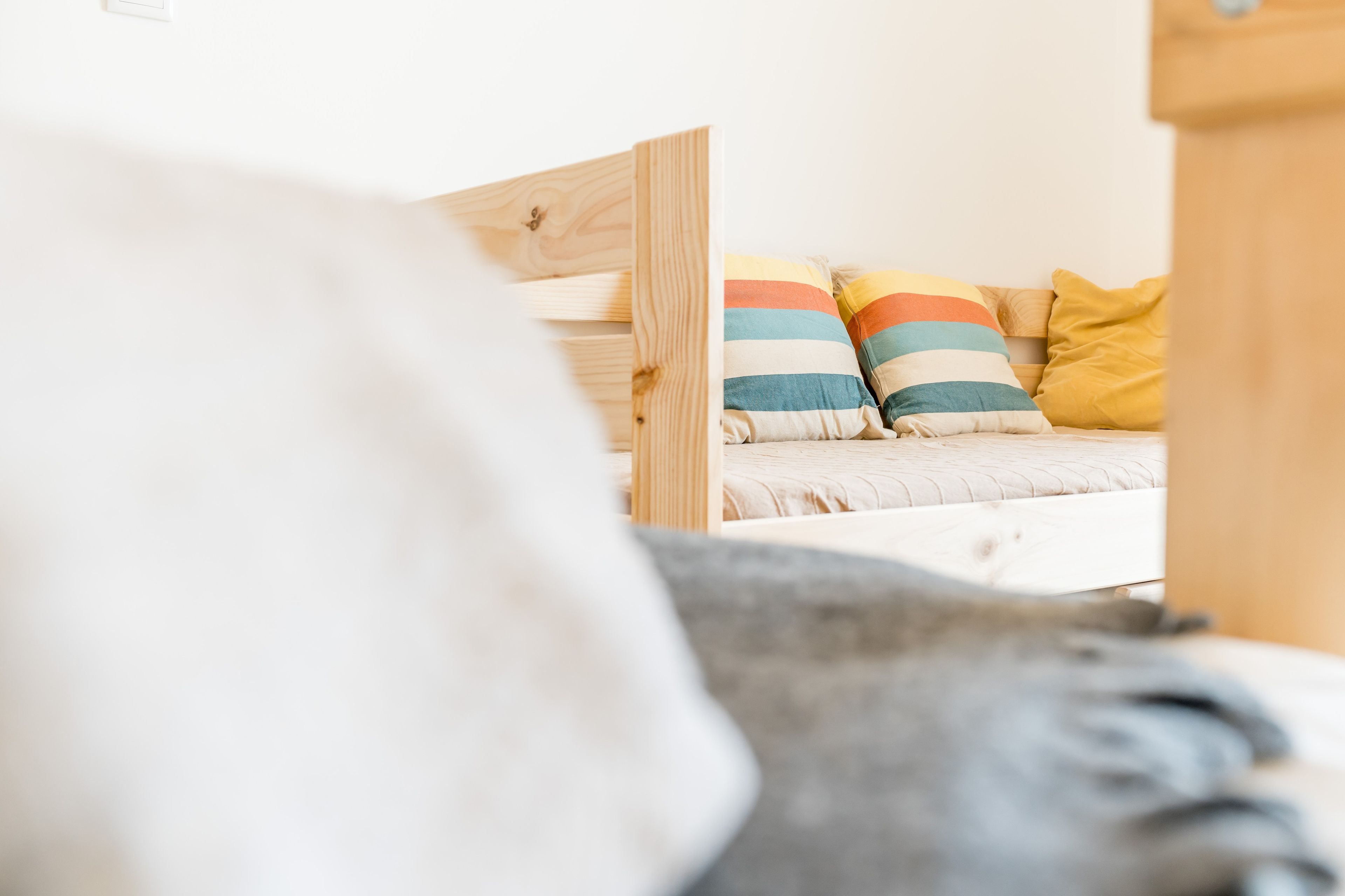 Ein Bett mit einem hölzernen Kopfteil und mehreren Kissen, darunter gestreifte und einfarbige.