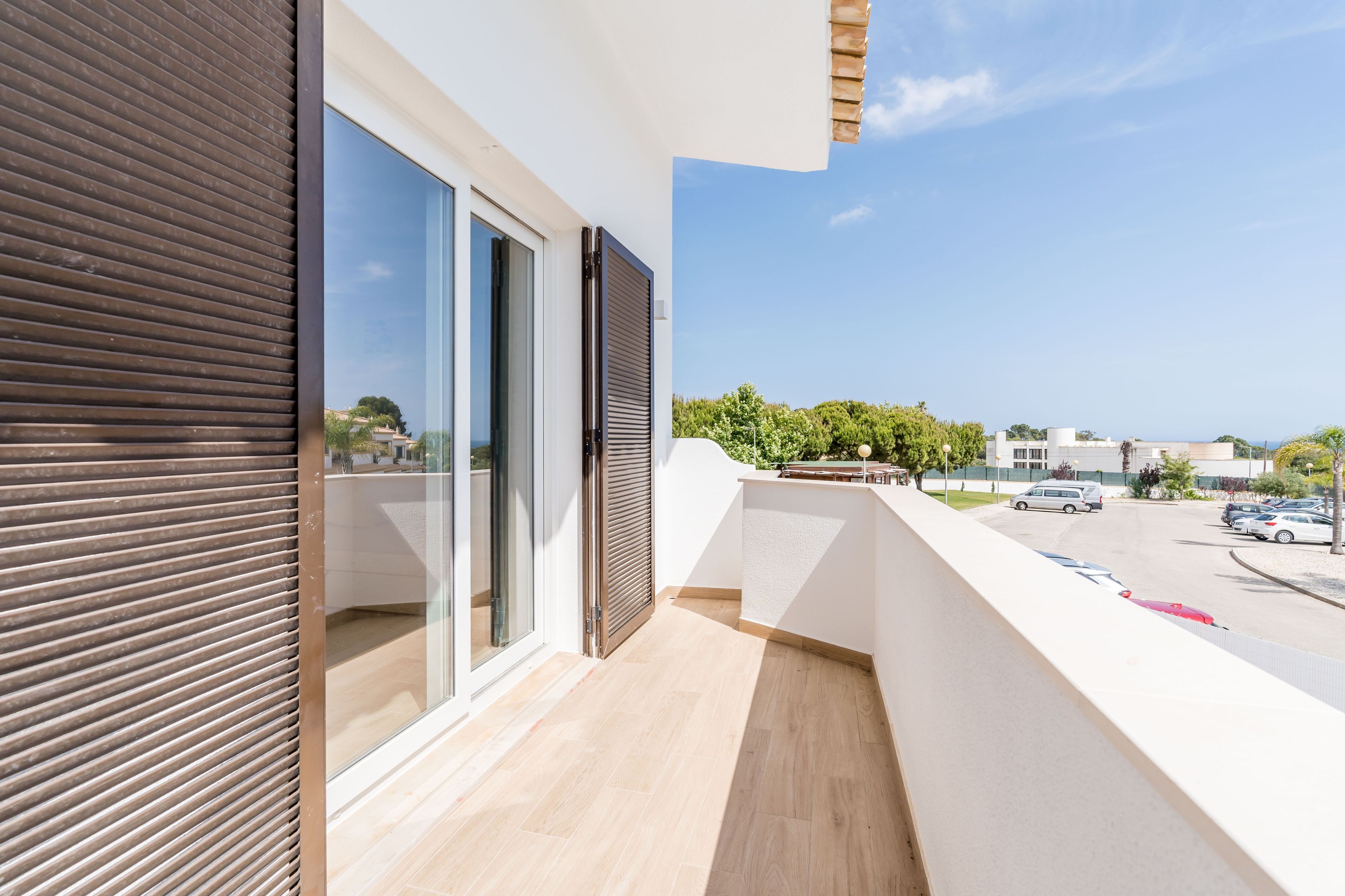 Ein Balkon mit Blick auf einen Parkplatz und Gebäude in der Ferne.