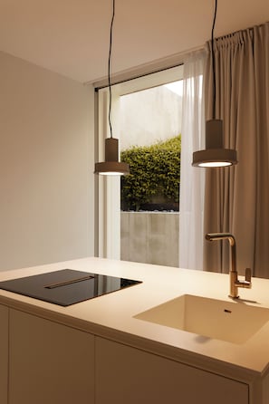 A modern kitchen with a large window, a built-in stove, and pendant lighting.