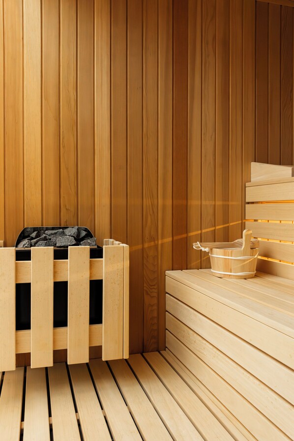 A sauna room with wooden benches and a bench with a black bag on it.