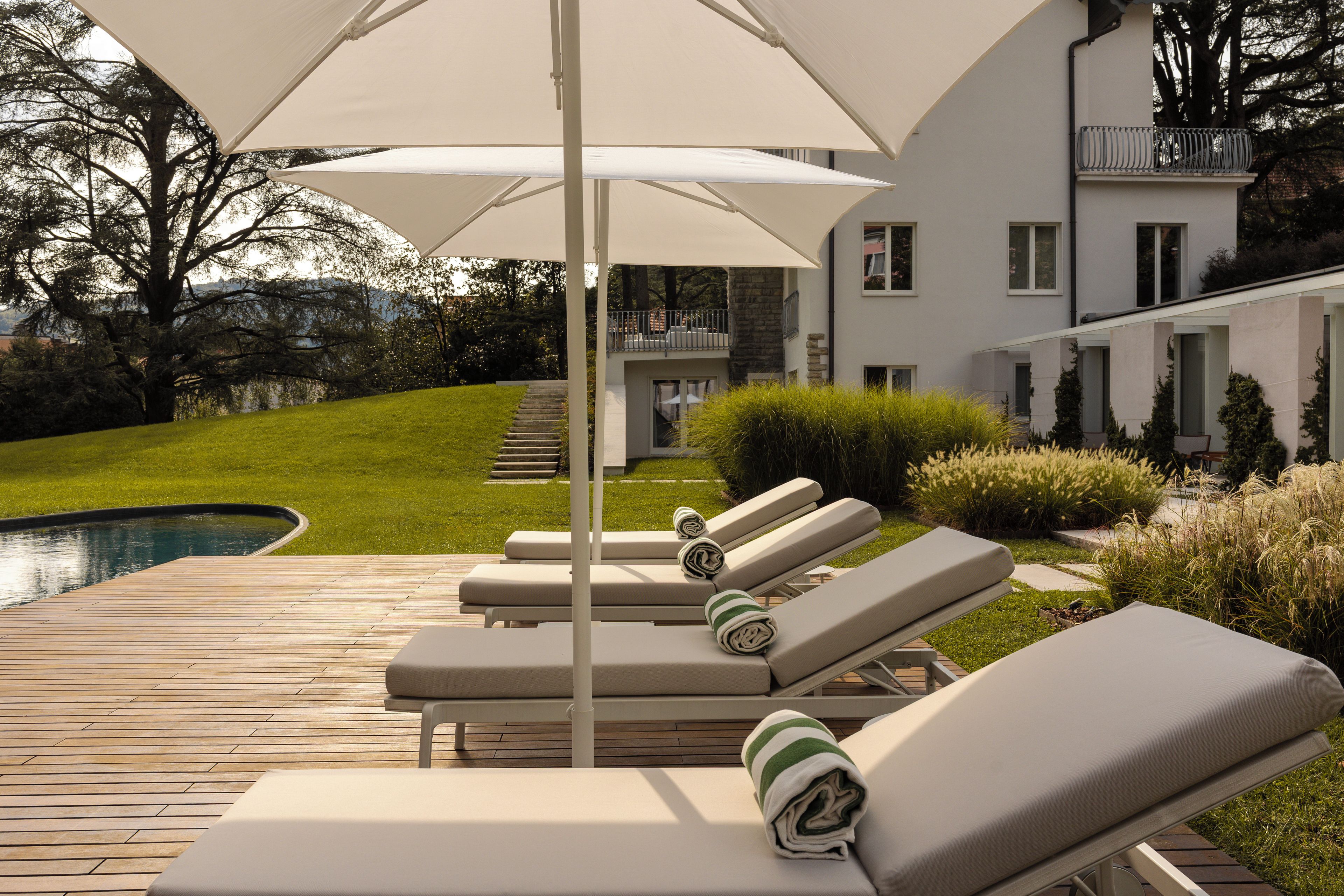 Un espace aménagé au bord de la piscine, avec des chaises longues et un grand parasol.