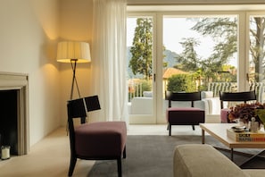 A living room with a fireplace, a floor lamp, and a view of the outdoors through a glass door.