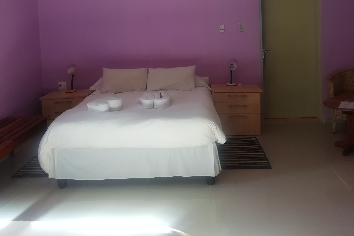 A bedroom with a bed, bedside tables, a door, and a chair.