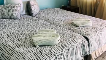 Ein ordentlich bezogenes Bett mit einem gemusterten Überwurf, zwei Kissen und gefalteten Handtüchern.