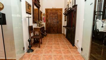 Un pasillo con puerta de madera, una pequeña mesa con sillas y una lámpara de pie.