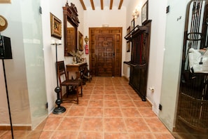 A hallway with a wooden door, a small table with chairs, and a floor lamp.
