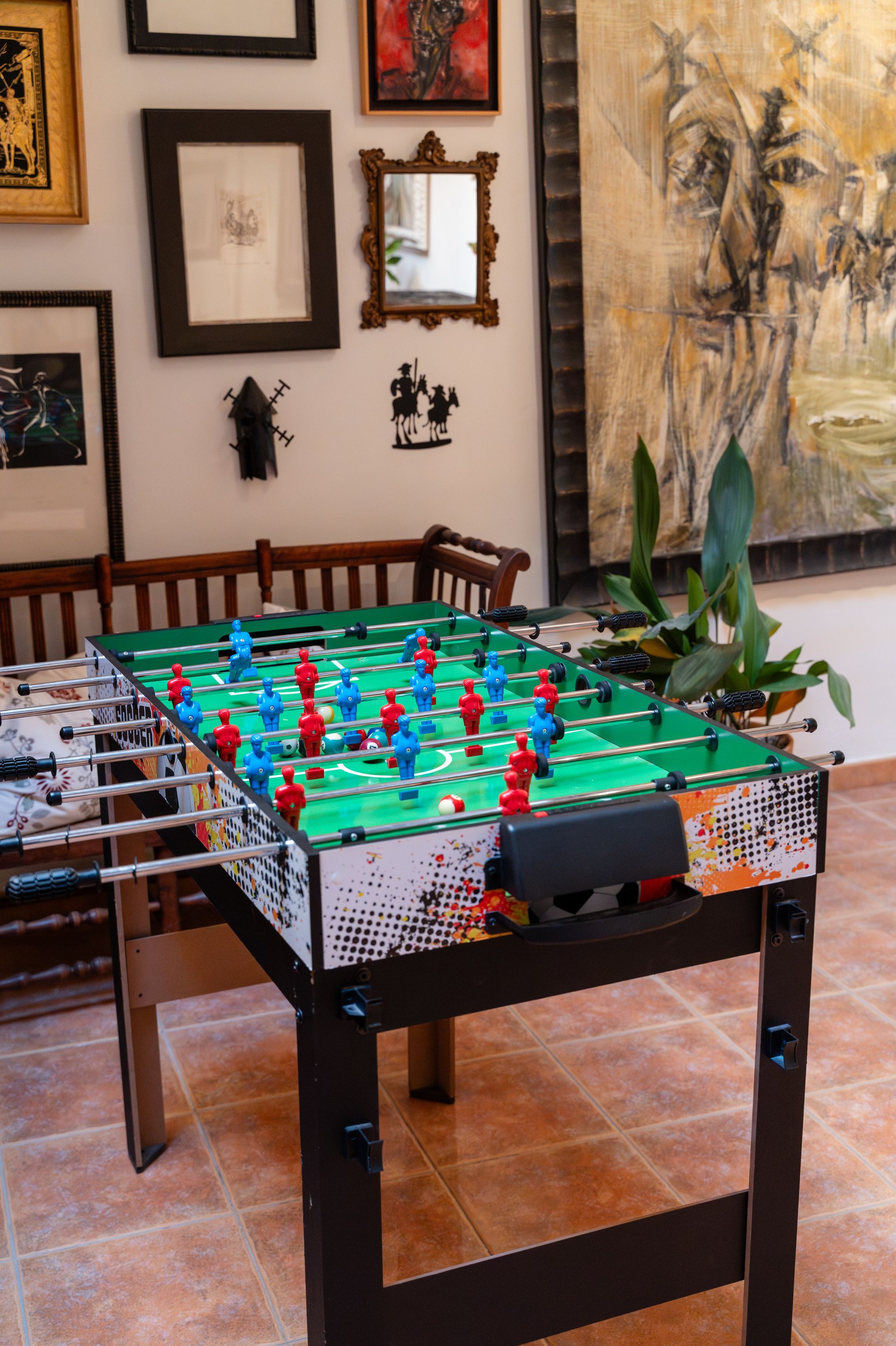Una mesa de fútbol de mesa en una habitación con obras de arte enmarcadas en las paredes.
