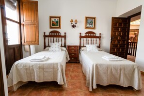 A double room with two beds, a wooden wardrobe, a nightstand, and a wall-mounted lamp.