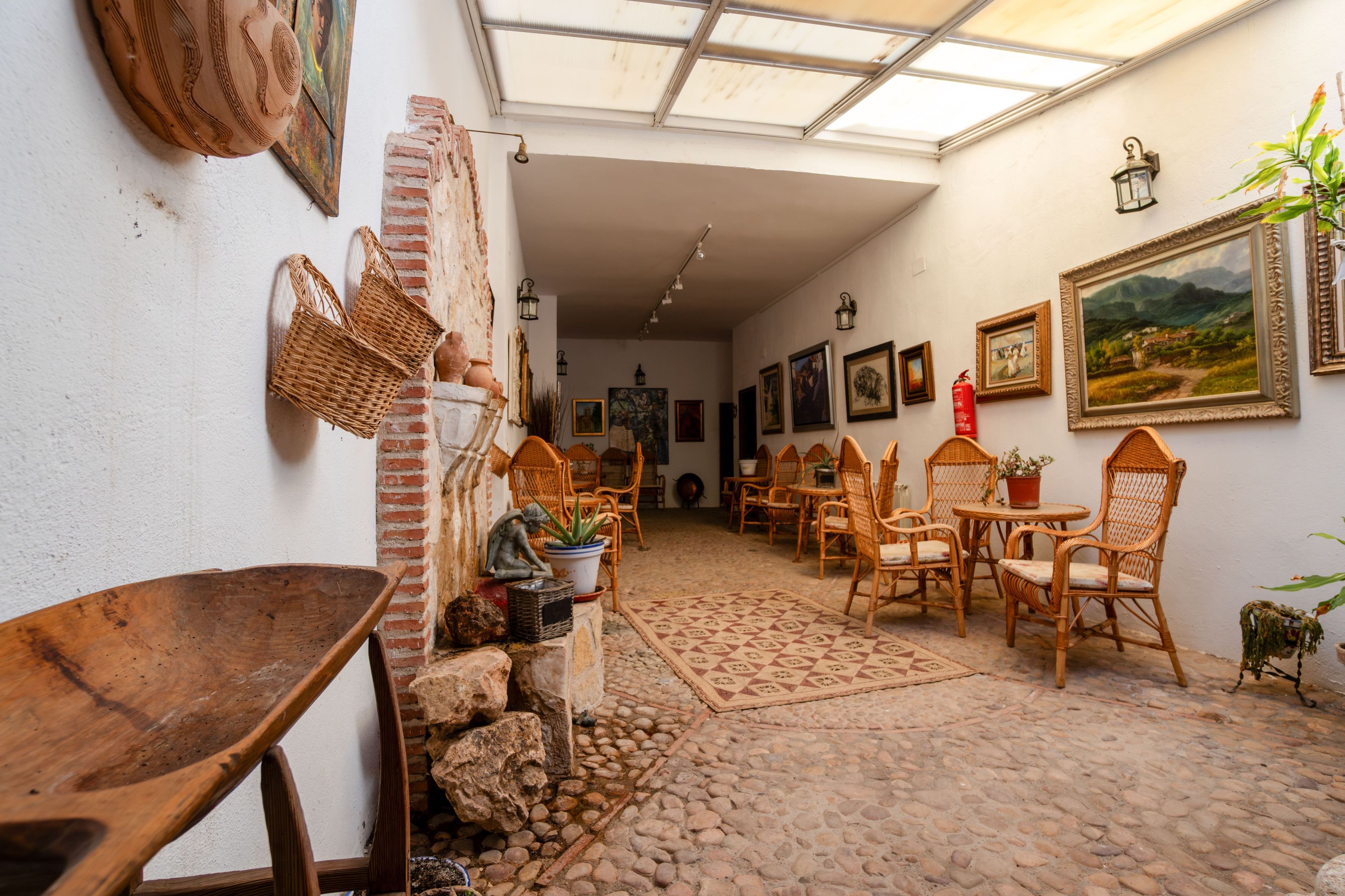 Un interior rústico con pared de ladrillo, muebles de mimbre y suelo de baldosas.