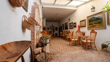 Un interior rústico con pared de ladrillo, muebles de mimbre y suelo de baldosas.