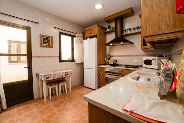 A kitchen with a refrigerator, stove, microwave, and wooden cabinets.