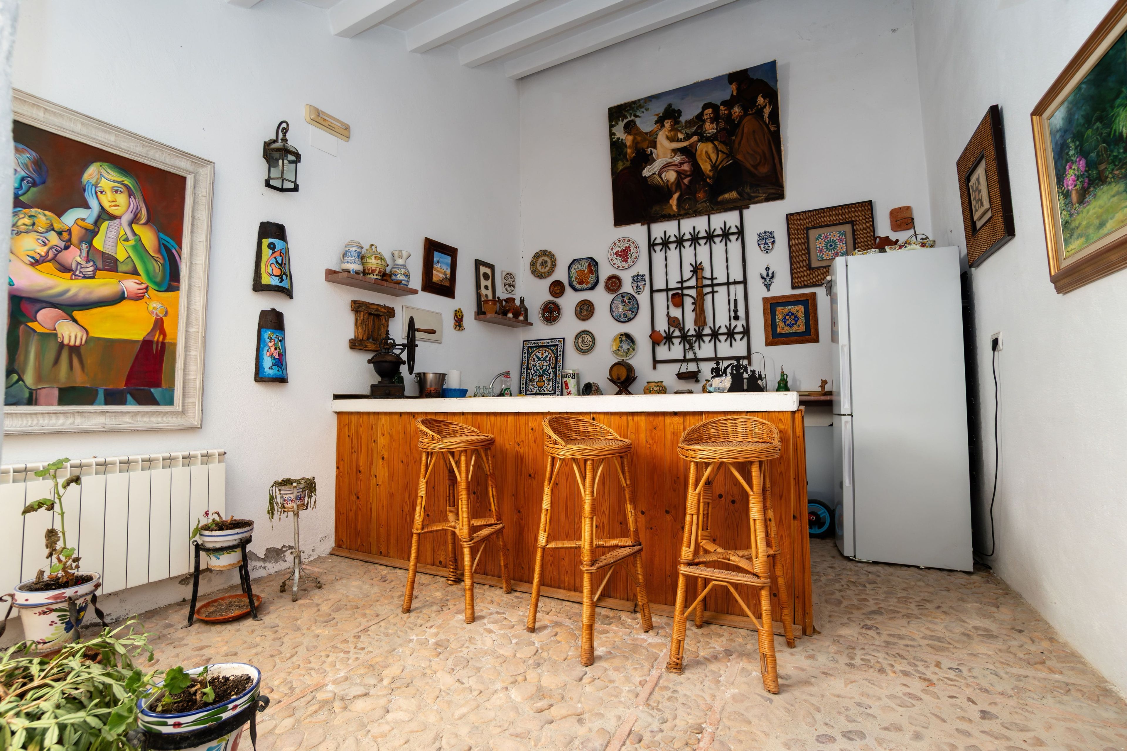 Una cocina con barra, taburetes de madera y varios objetos decorativos en las paredes.