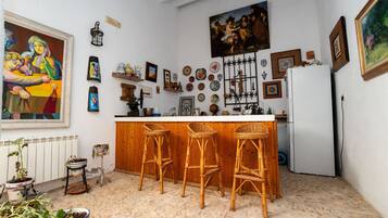 Una cocina con barra, taburetes de madera y varios objetos decorativos en las paredes.