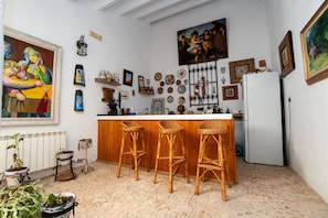 A kitchen with a bar area, wooden stools, and various decorative items on the walls.