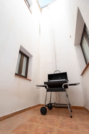 A small, enclosed patio area with a portable barbecue grill and a window.