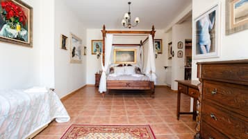 Un dormitorio con una cama con dosel, una mesita de noche, un aparador y una alfombra grande.