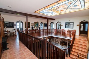 A spacious interior with a staircase, wooden railings, and a stained glass ceiling.