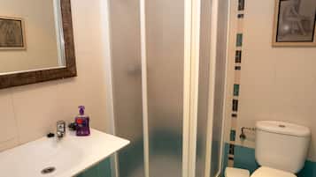 Un baño con cabina de ducha, inodoro, lavabo y espejo.