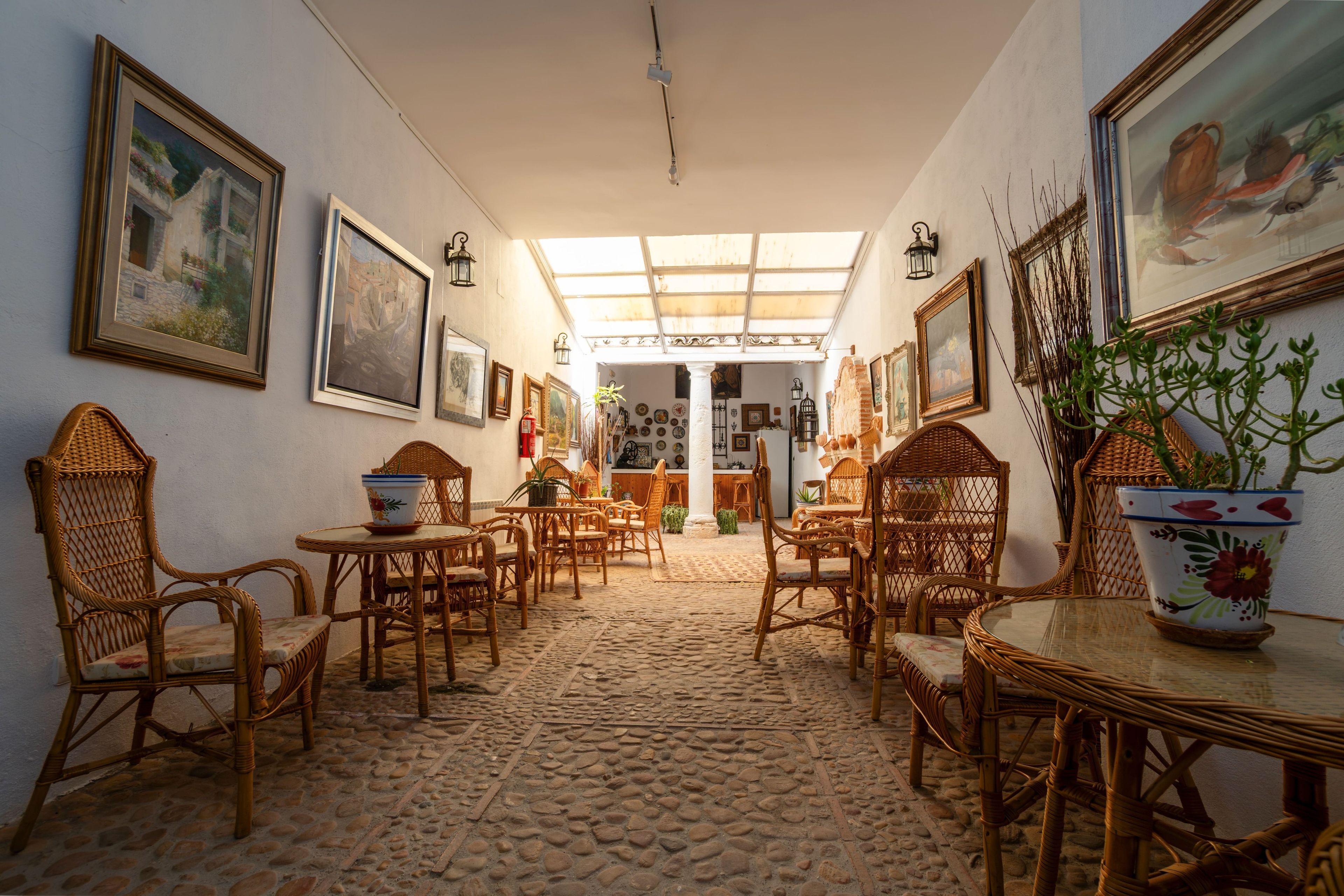 A room with wicker furniture, a tiled floor, and framed artwork on the walls.